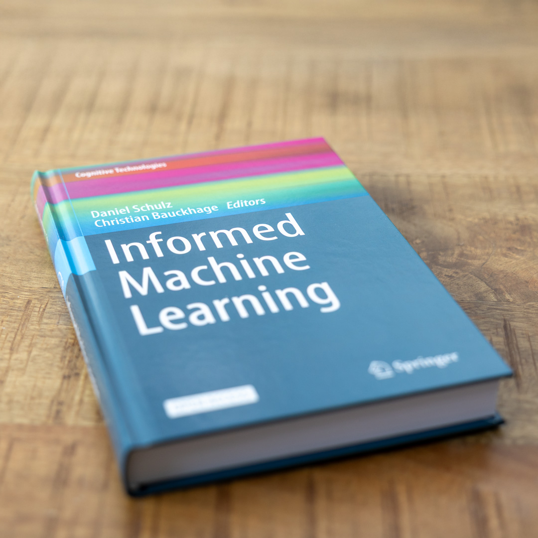 Buch »Informed Machine Learning« Ein Buch mit mehrfarbigem Cover liegt auf einem Tisch. Der Titel lautet »Informed Machine Learning«.